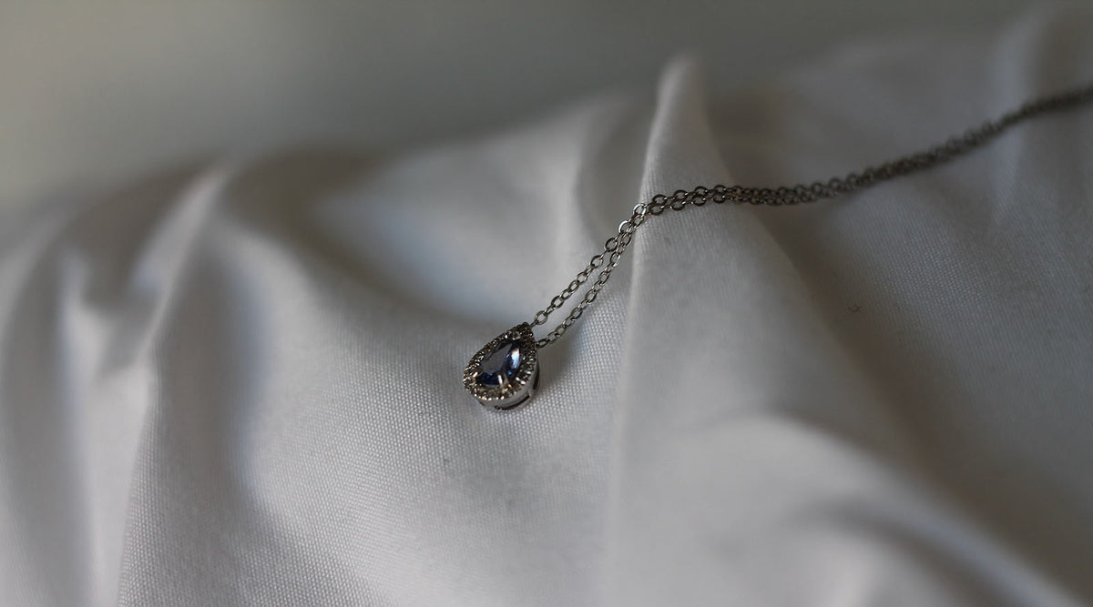 silver pendant necklace on white fabric