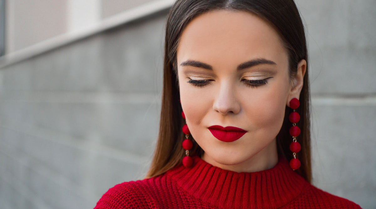 brunetter wearing red drop earrings red lipstick and red top