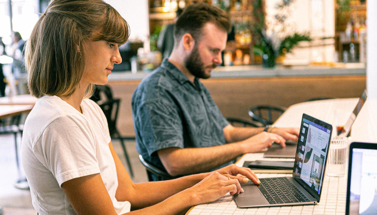 female and male digital marketers typing on their laptops