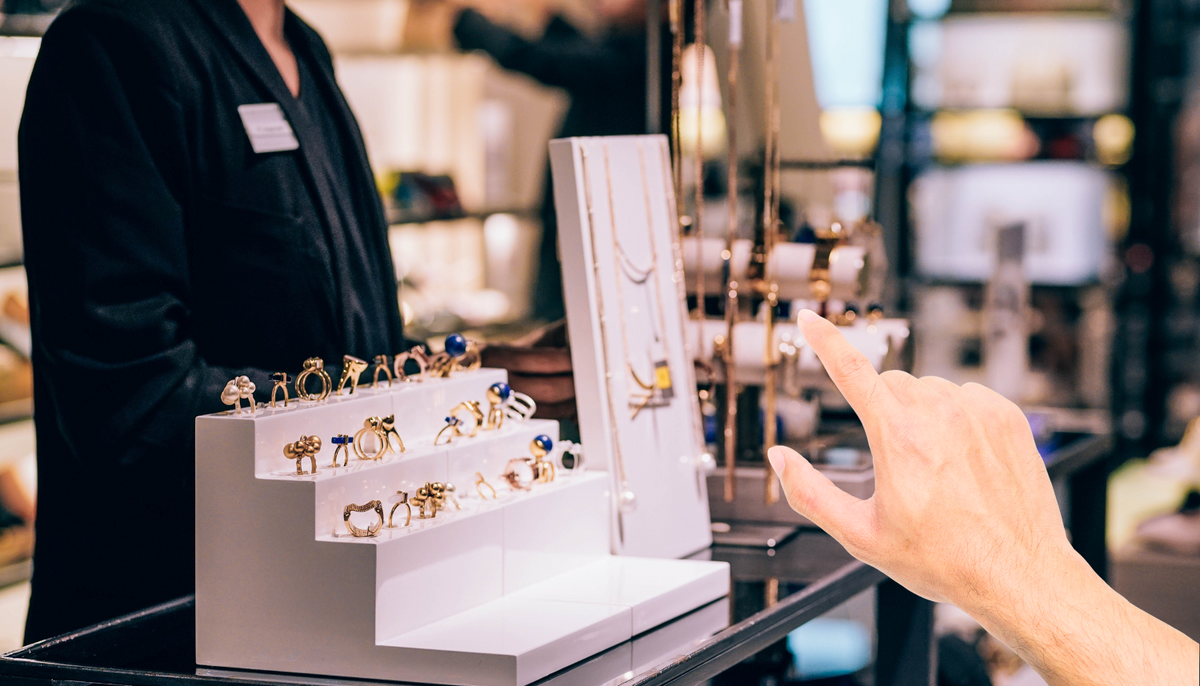 hand pointing to the necklaces on the display inside a fashion jewelry store