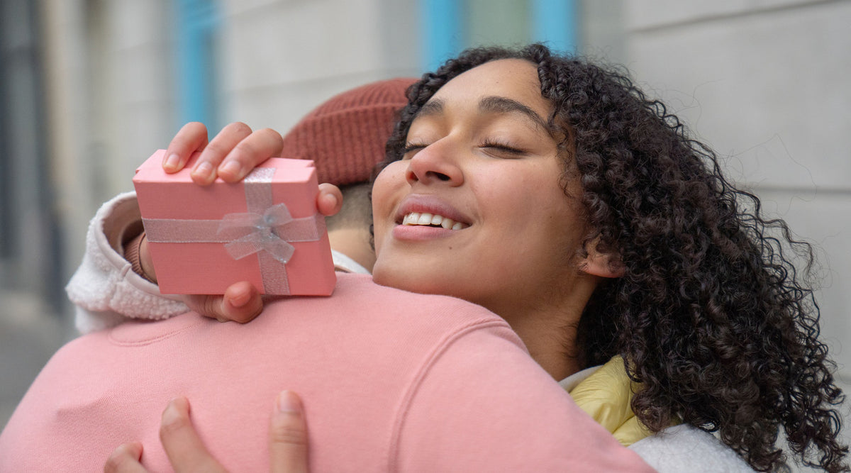 loving-hispanic-woman-with-gift-box-hugging-unrecognizable-man