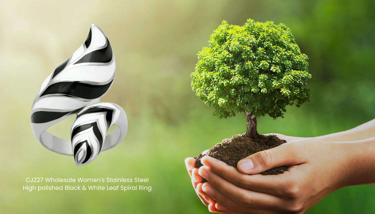 person's hands holding a small tree with the CJ227 Stainless Steel High polished Black & White Leaf Spiral Ring on the left side