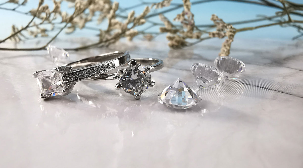 two cubic zirconia fashion rings and cz crystals on white surface