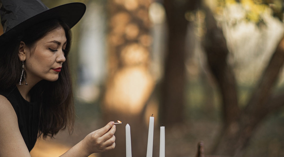 woman in black witch costume lighting a candle on table