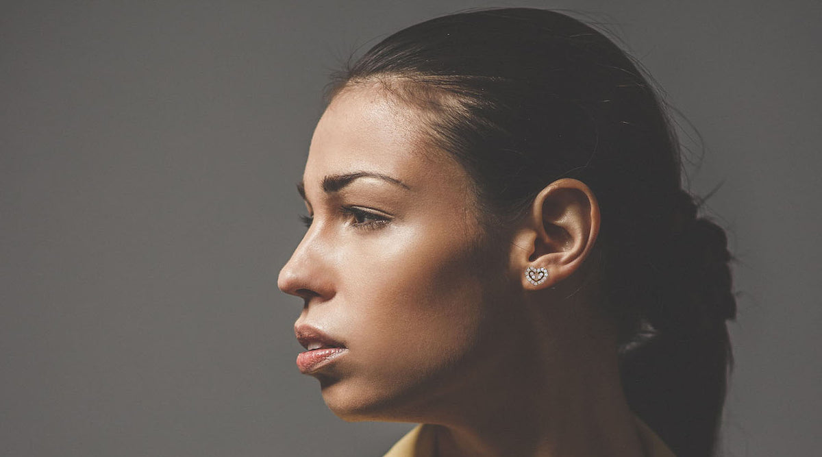 woman in a pony tail wearing heart stud earrings side profile