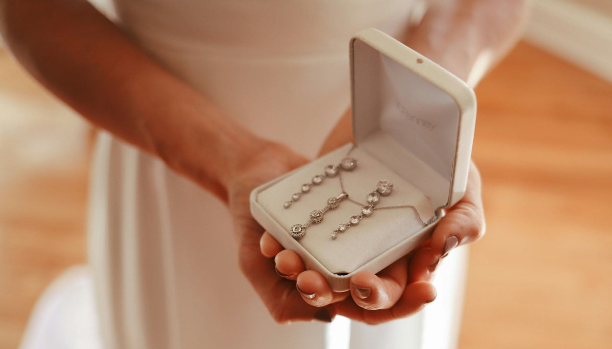 woman in a white dress holding an open white velveteen jewelry box with swarovski elements jewelry set