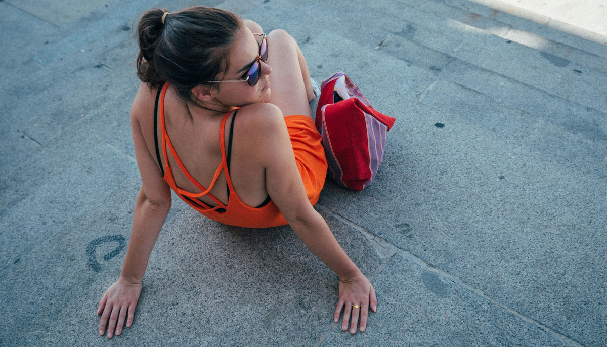 woman in an orange summer dress and gold plated fashion ring sitting on steps