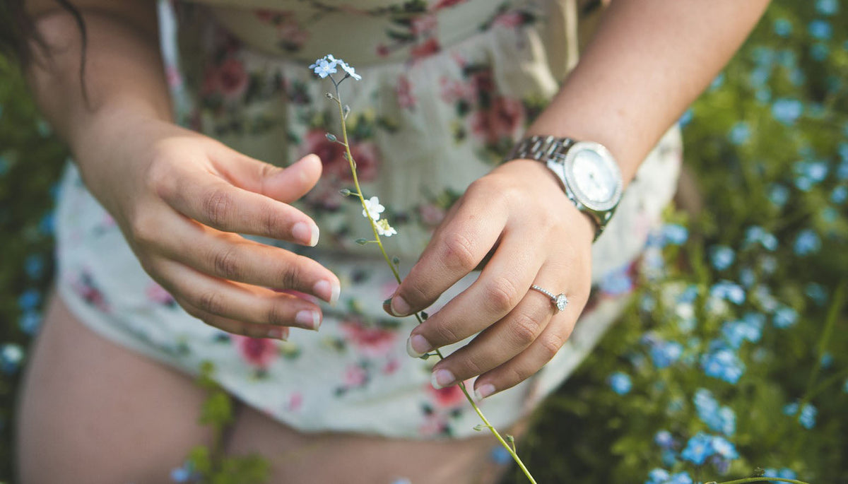 woman wearing a floral dress and fashion rings holding white flowers during daytime