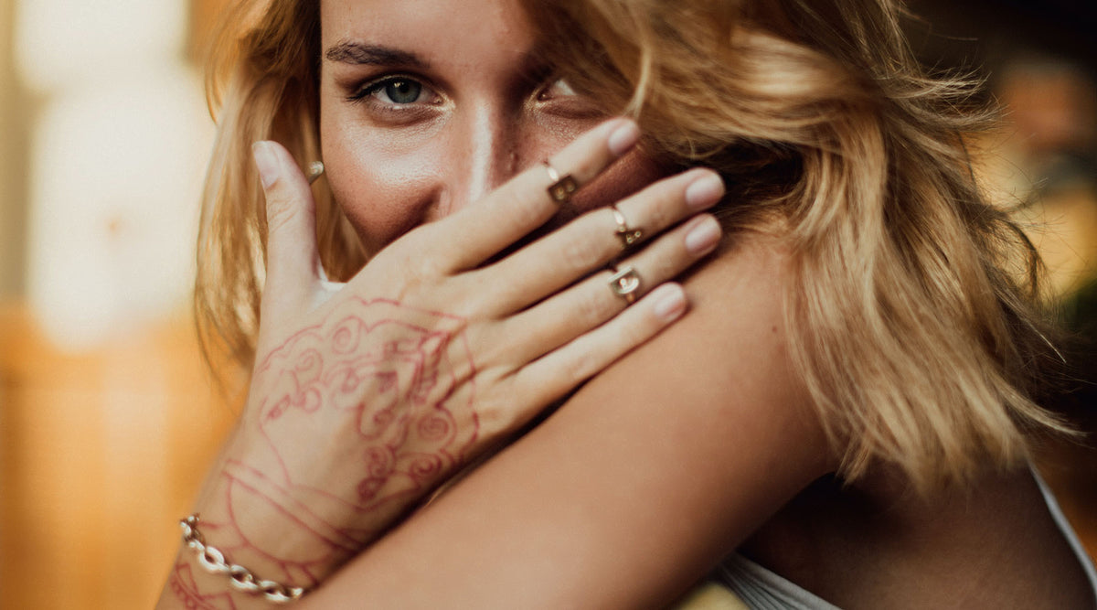 woman wearing minimalist fashion rings covering her mouth with hand