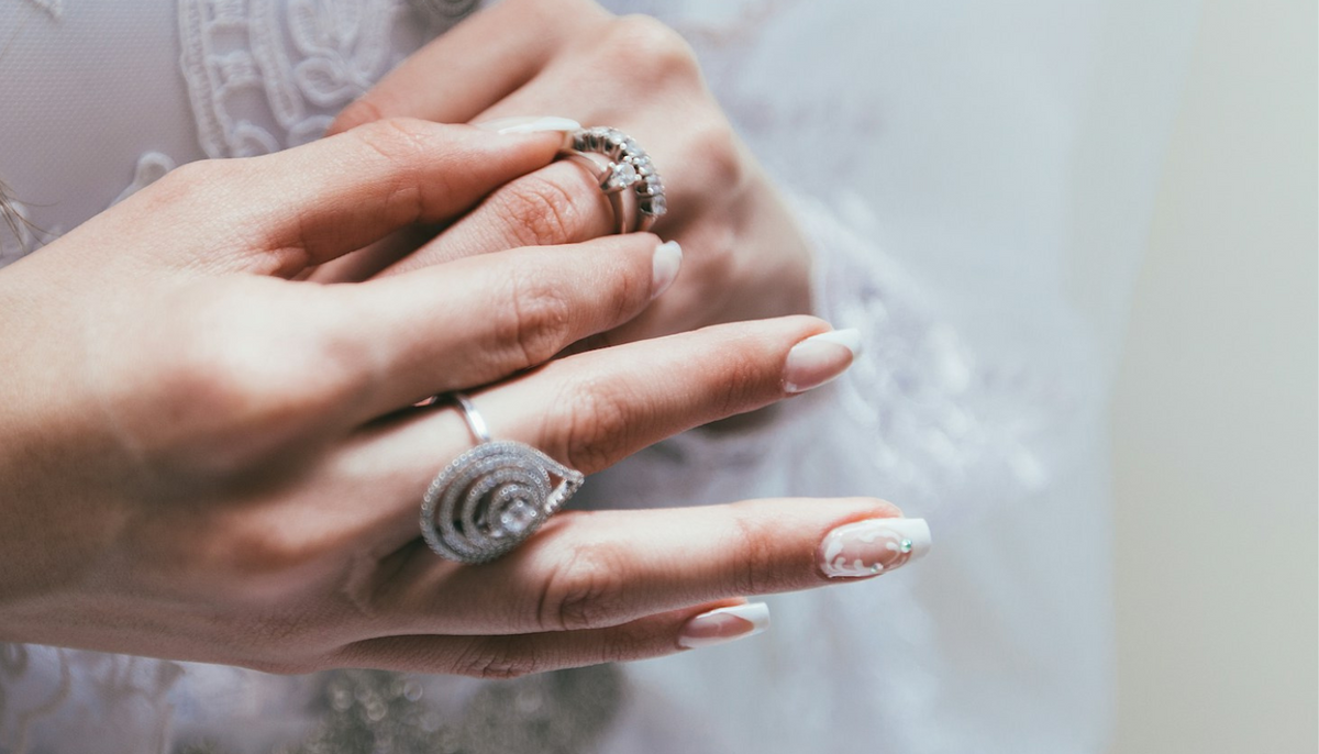 woman with manicured nails trying on some fashion rings