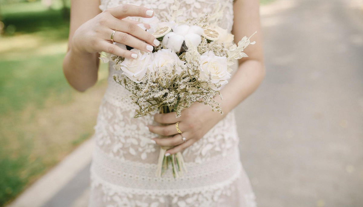 Woman in White Dress Holding a Bouquet of Flowers and wearing a floral fashion ring and other rings