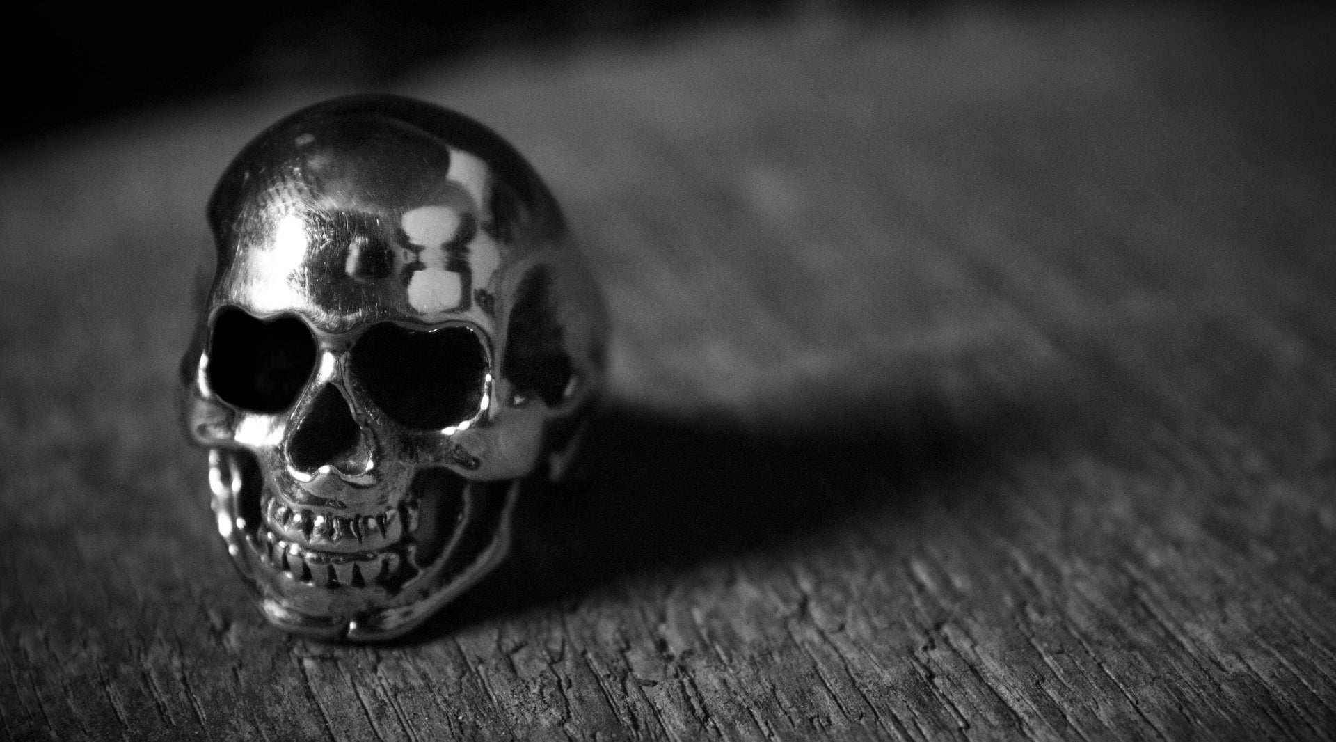 black and white photo of a skull ring on a wooden surface