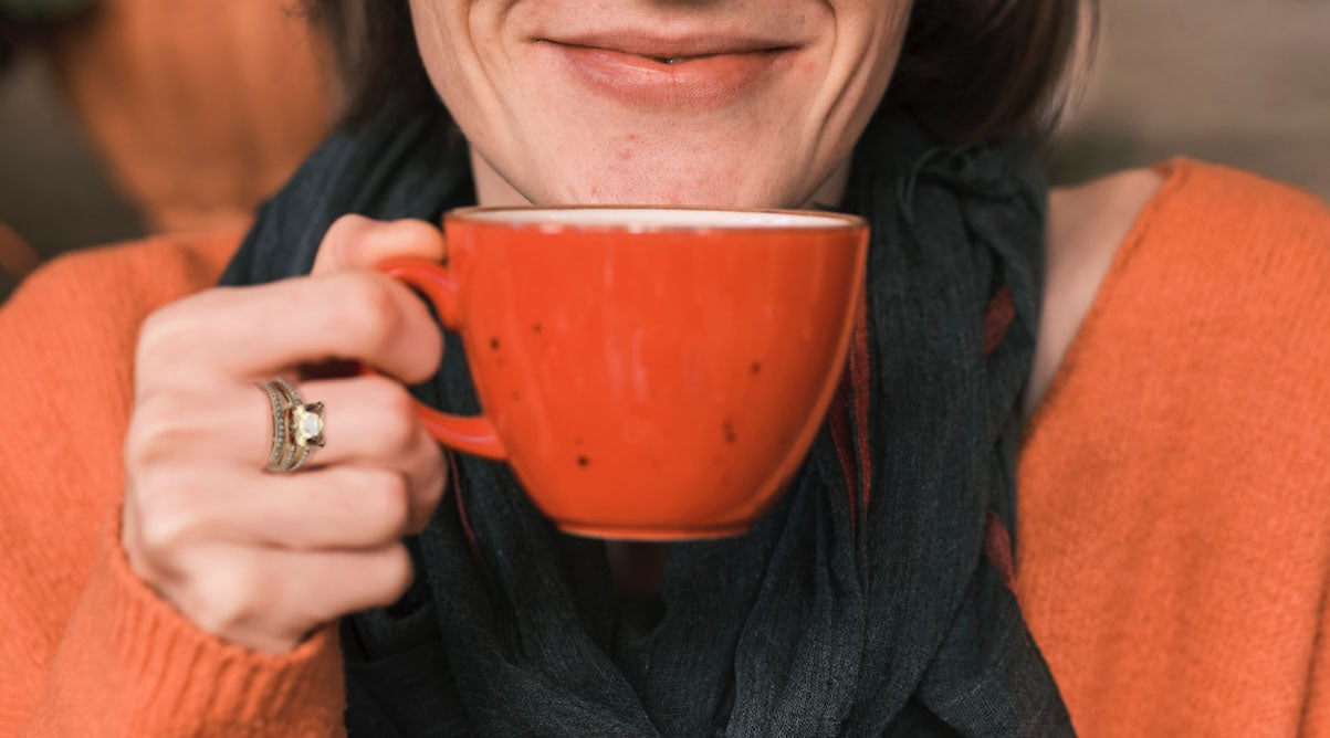 close up photo of smiling woman wearing rose gold cz ring holding red cup to her mouth