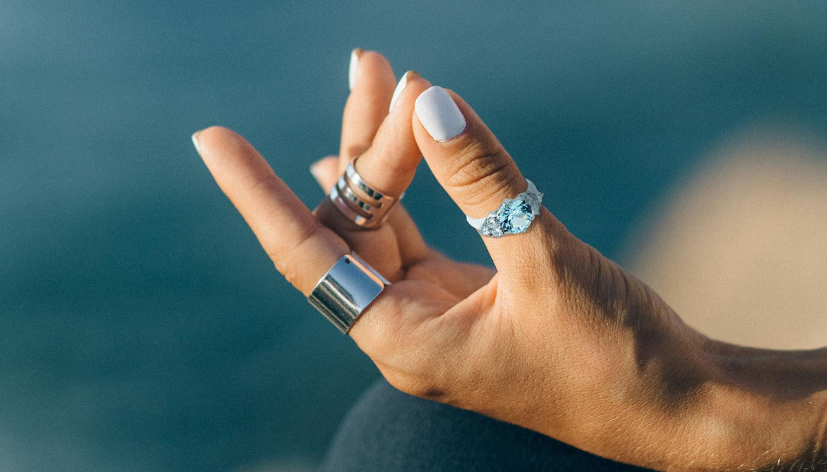close up shot of a woman's hand in yoga position and wearing rings one is the CJ134TK Wholesale Stainless Steel Aquamarine Cubic Zirconia Ring