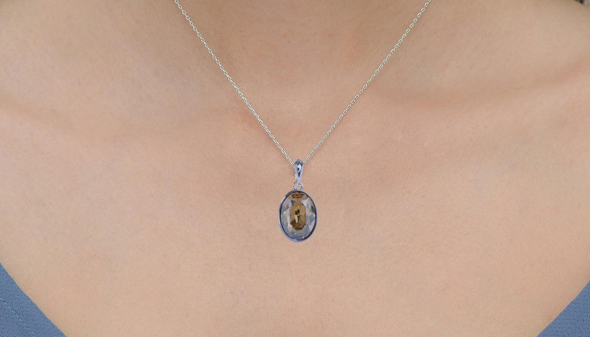 close up shot of a woman's upper chest and neck wearing CeriJewelry's Swarovski Elements pendant necklace in chanpagne