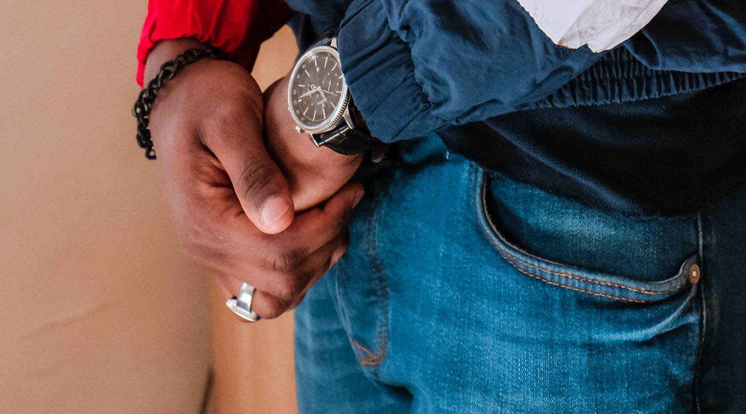 close up shot of man's hand wearing a fashion ring, black bracelet, and a watch