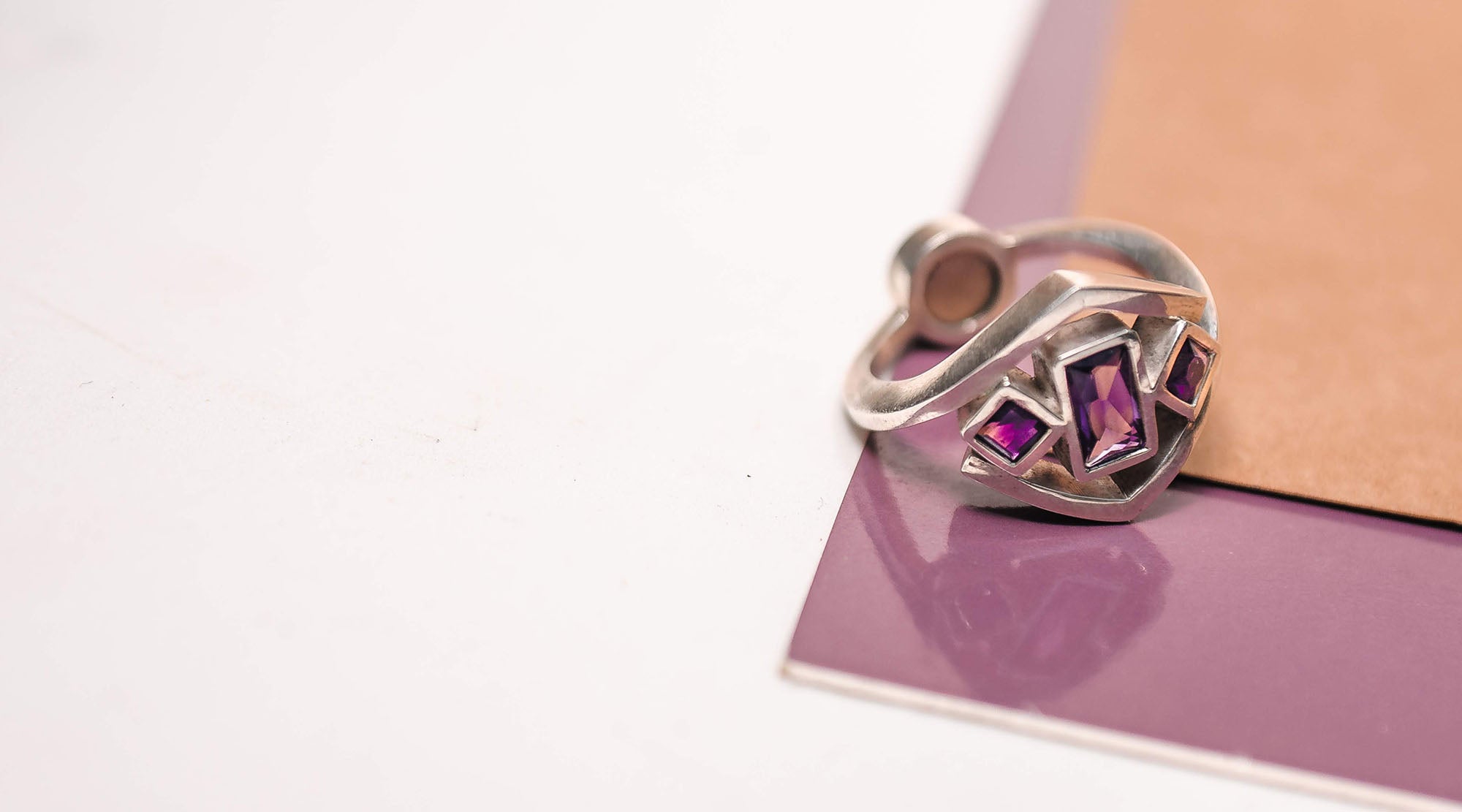 fashion ring with purple crystals placed on purple surface