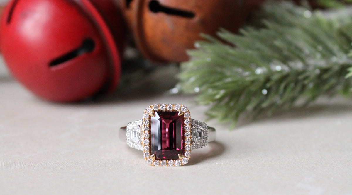 garnet fashion ring on white surface with red bells at the background