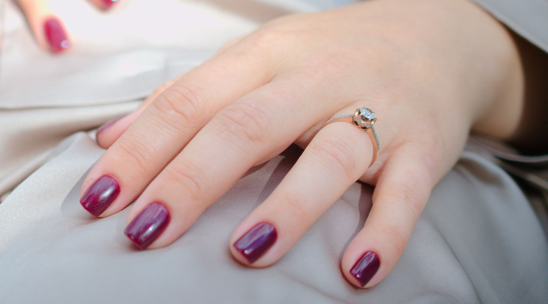 hand of a woman with wine red nail polish and engagement ring