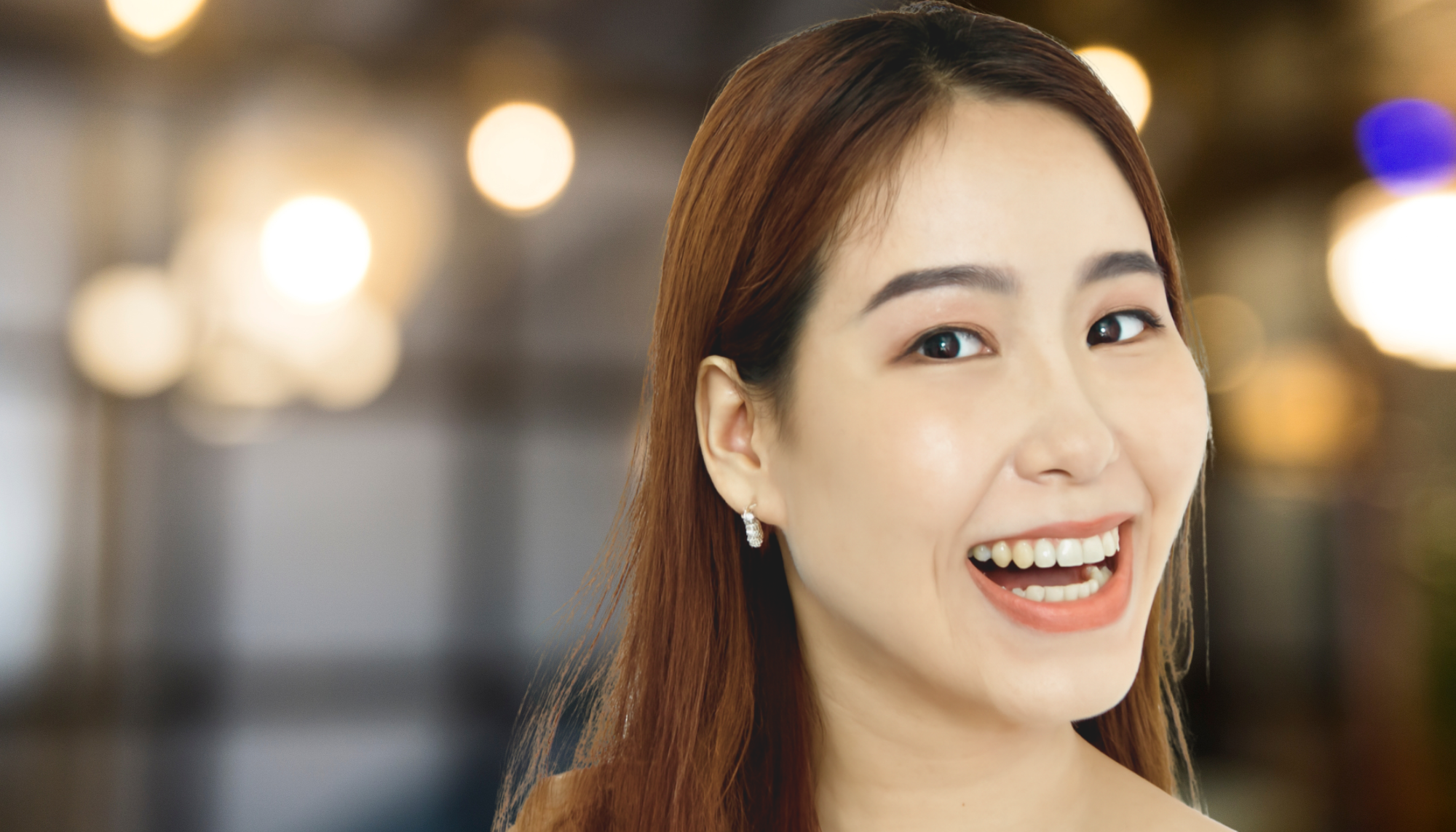 laughing woman against bokeh background wearing minimalist hoop earrings 
