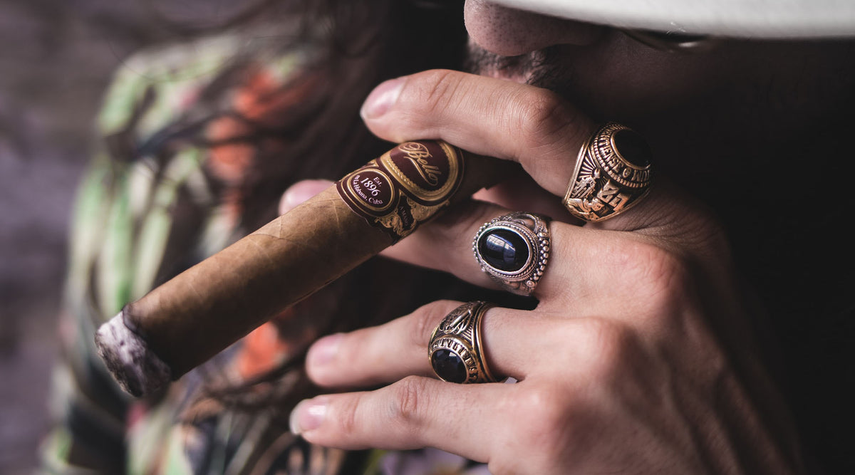 man wearing fashion rings and white hat holding cigar