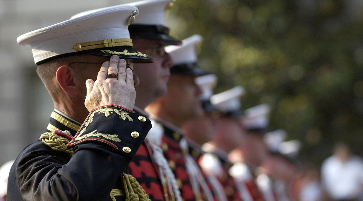 military people saluting with one wearing a black-plated military ring