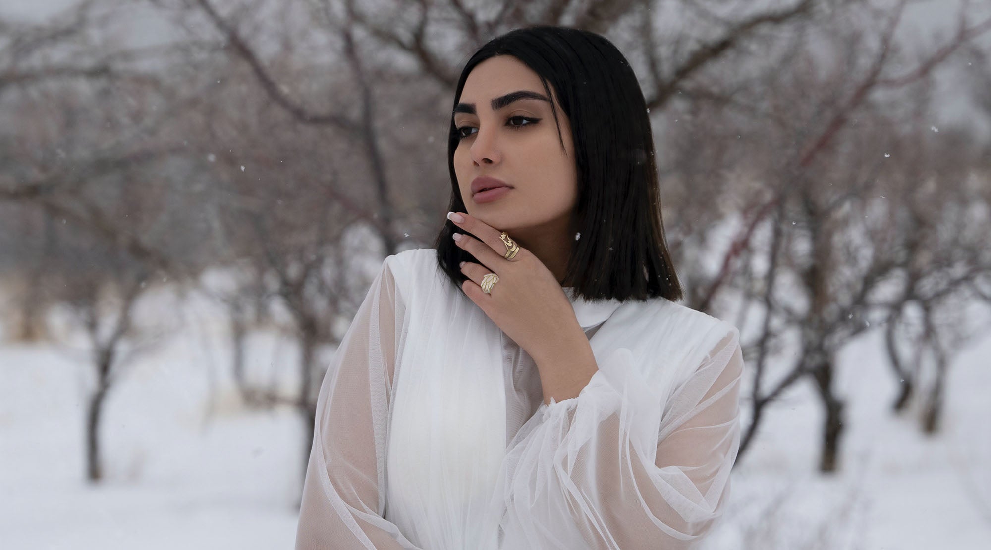 woman in white dress wearing a white epoxy fashion ring and gold ring outside in the snow