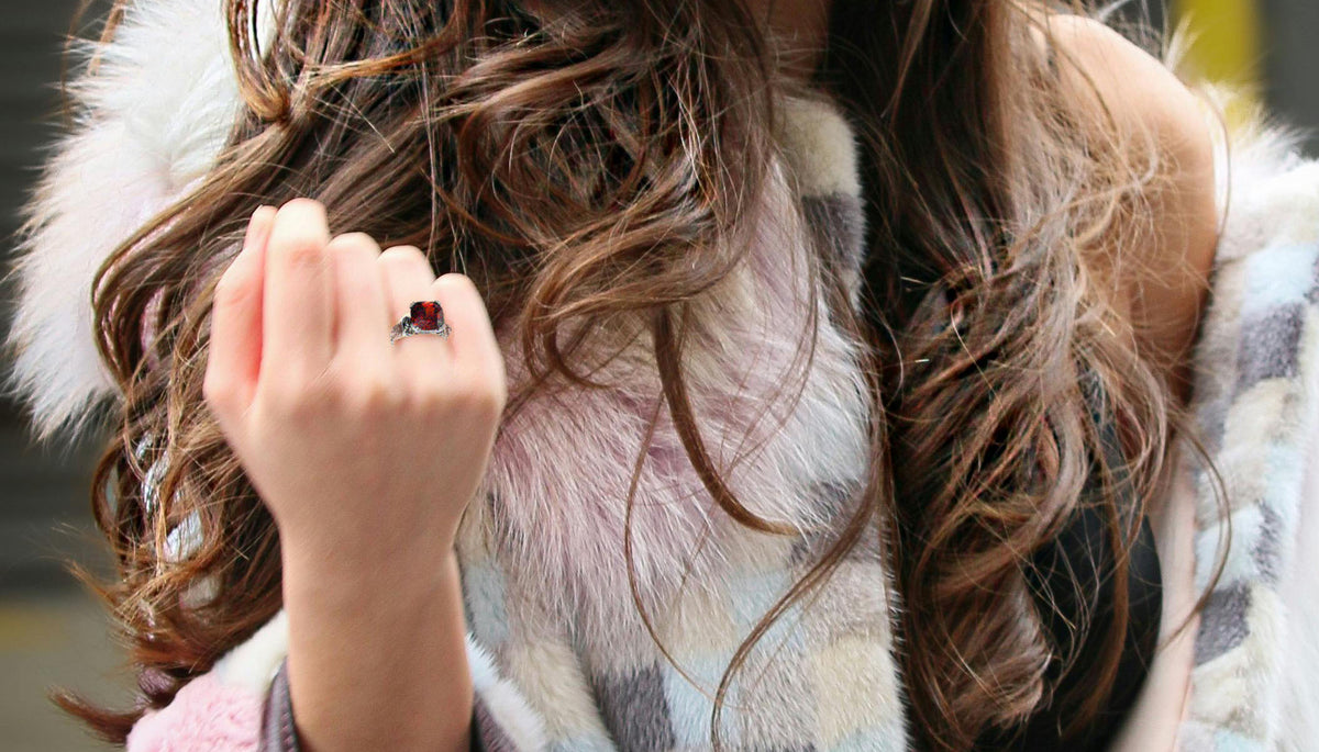 woman in faux fur coat wearing CeriJewelry's CJ7703OS Stainless Steel Ornate Cushion Garnet CZ Cocktail Ring