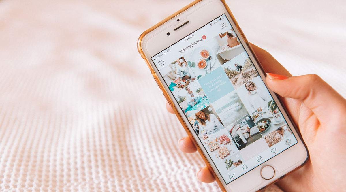 woman's hand holding smartphone with the screen showing an Instagram feed