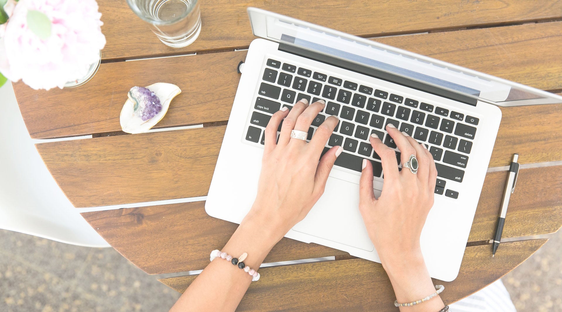 woman wearing fashion jewelry typing on a laptop