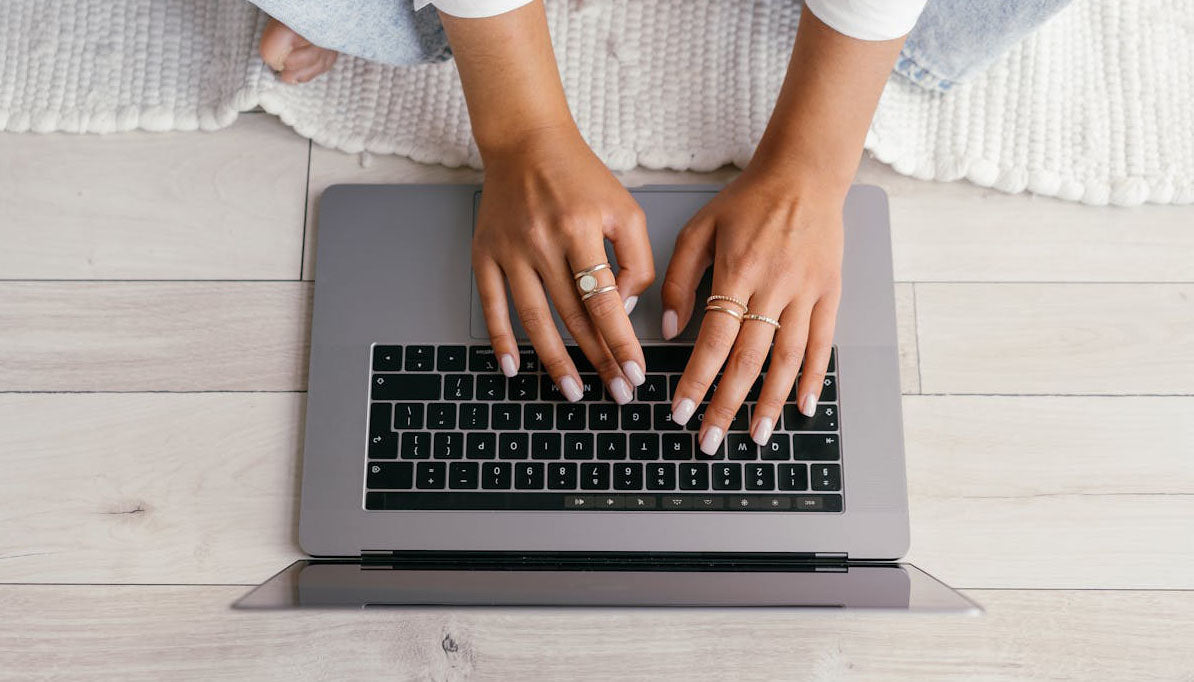 woman wearing fashion rings typing on laptop