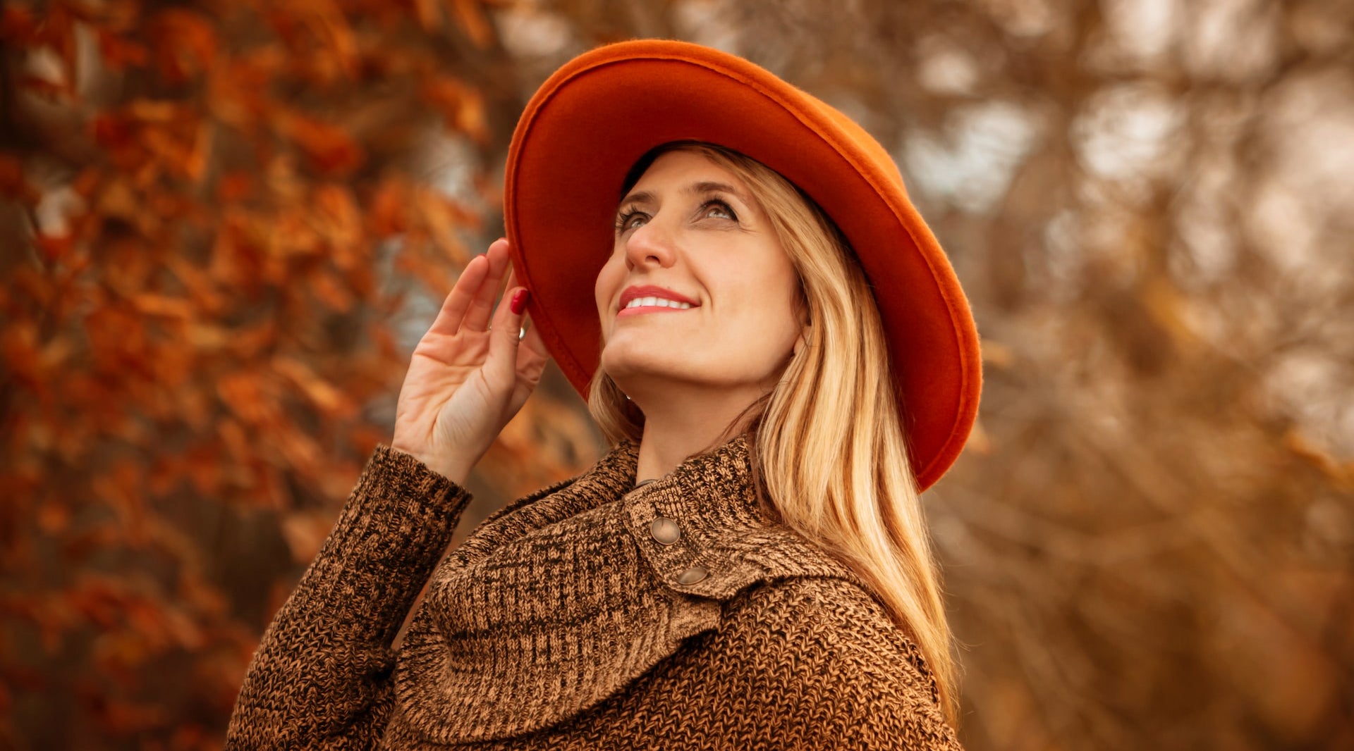woman wearing orange hat and brown sweater in autumn