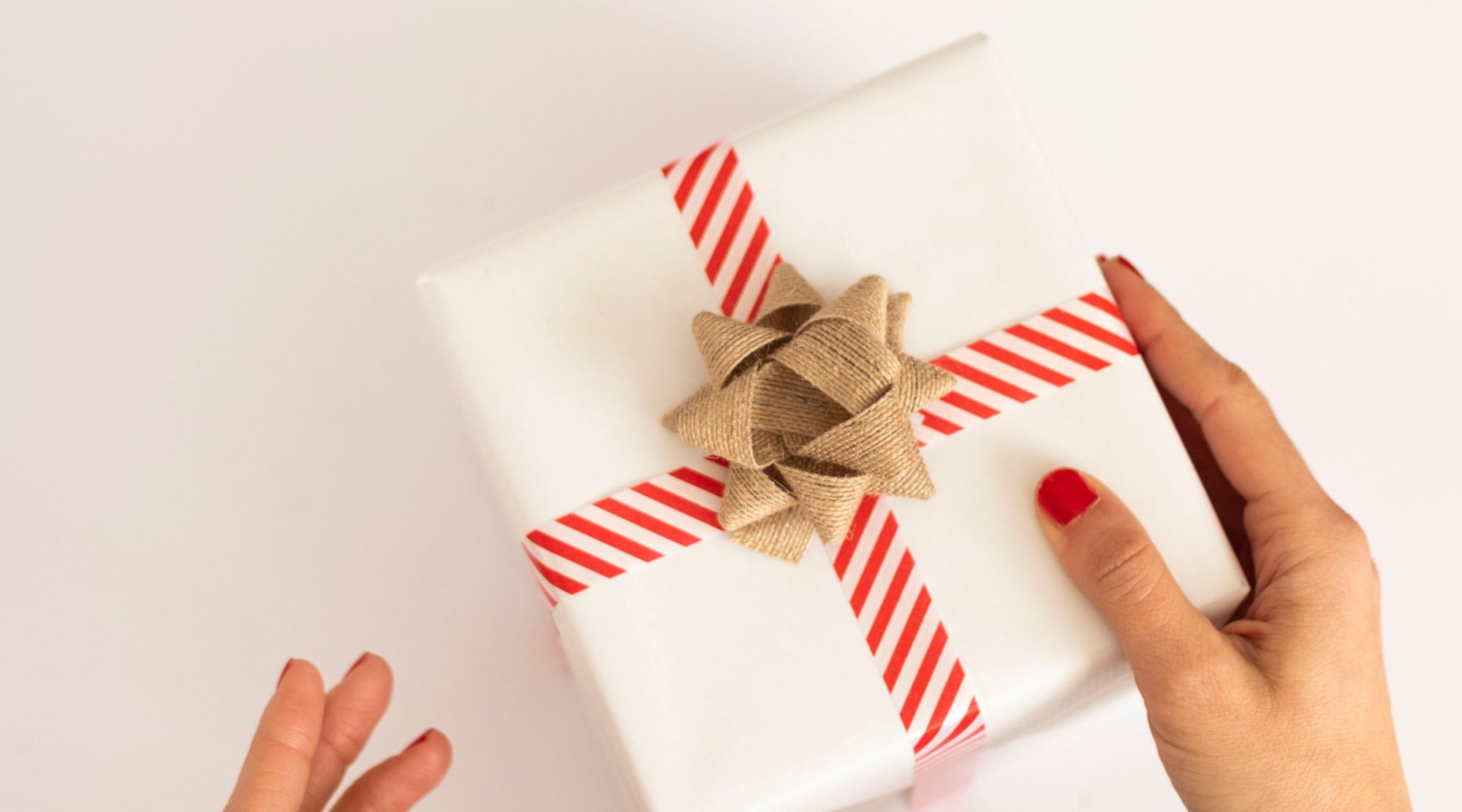 woman with red nails about to open a gift