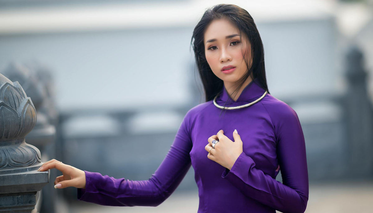 zoomed out photo of woman in a purple long-sleeved top wearing CeriJewelry wholesale fashion ring with solitaire light amethyst cz